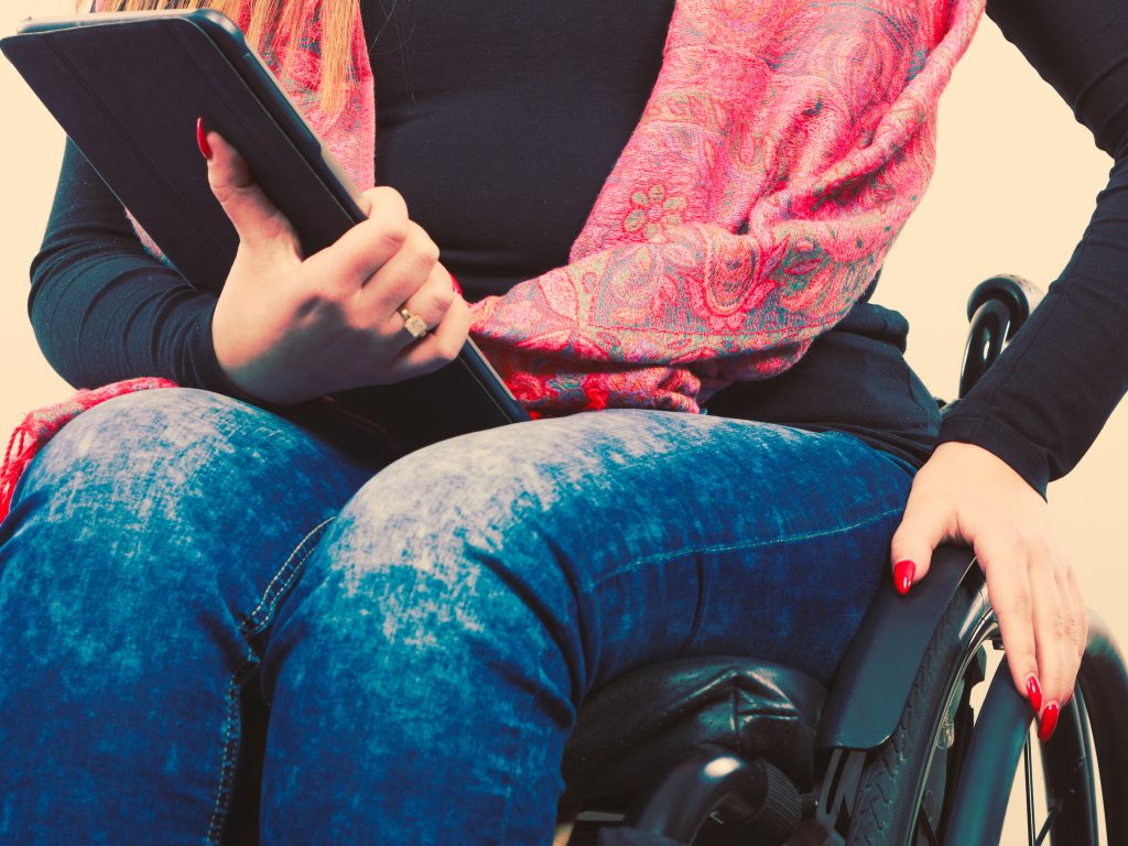 a disabled woman in a wheelchair holding a computer tablet