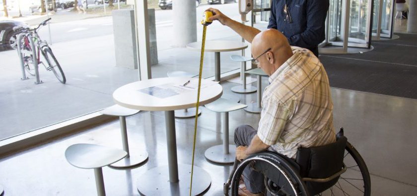 Man on wheelchair measuring table height at restaurant