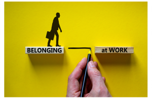 Belonging at work symbol. Wooden blocks with words 'Belonging at work' on beautiful yellow background. Businessman hand. Businessman icon. Business, belonging at work concept.