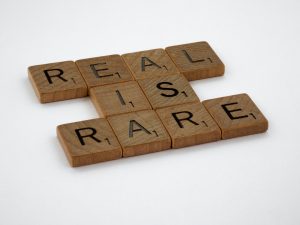 Scrabble tiles, spelling out "REAL IS RARE"