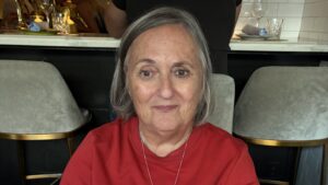 A close-up photo of business owner Pamela Shainhouse; Pamela is a mature Caucasian woman with chin-length silver hair. She wears a red sweater, a gold necklace, and a warm smile.