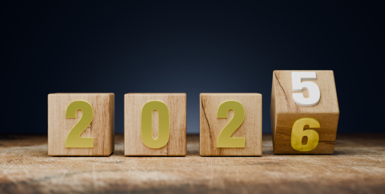 On a wooden table, 4 wooden blocks marked with golden numbers read out 2-0-2, with the fourth block visibly flipping from 5 to 6 as the year turns over.