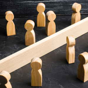 Image: A crowd of wooden figures are divided by a wooden board.