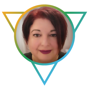 A staff photo of Jennifer Magee. She is a mature Caucasian woman with vibrant cropped, vibrant red-dyed hair, and wears a black blouse.